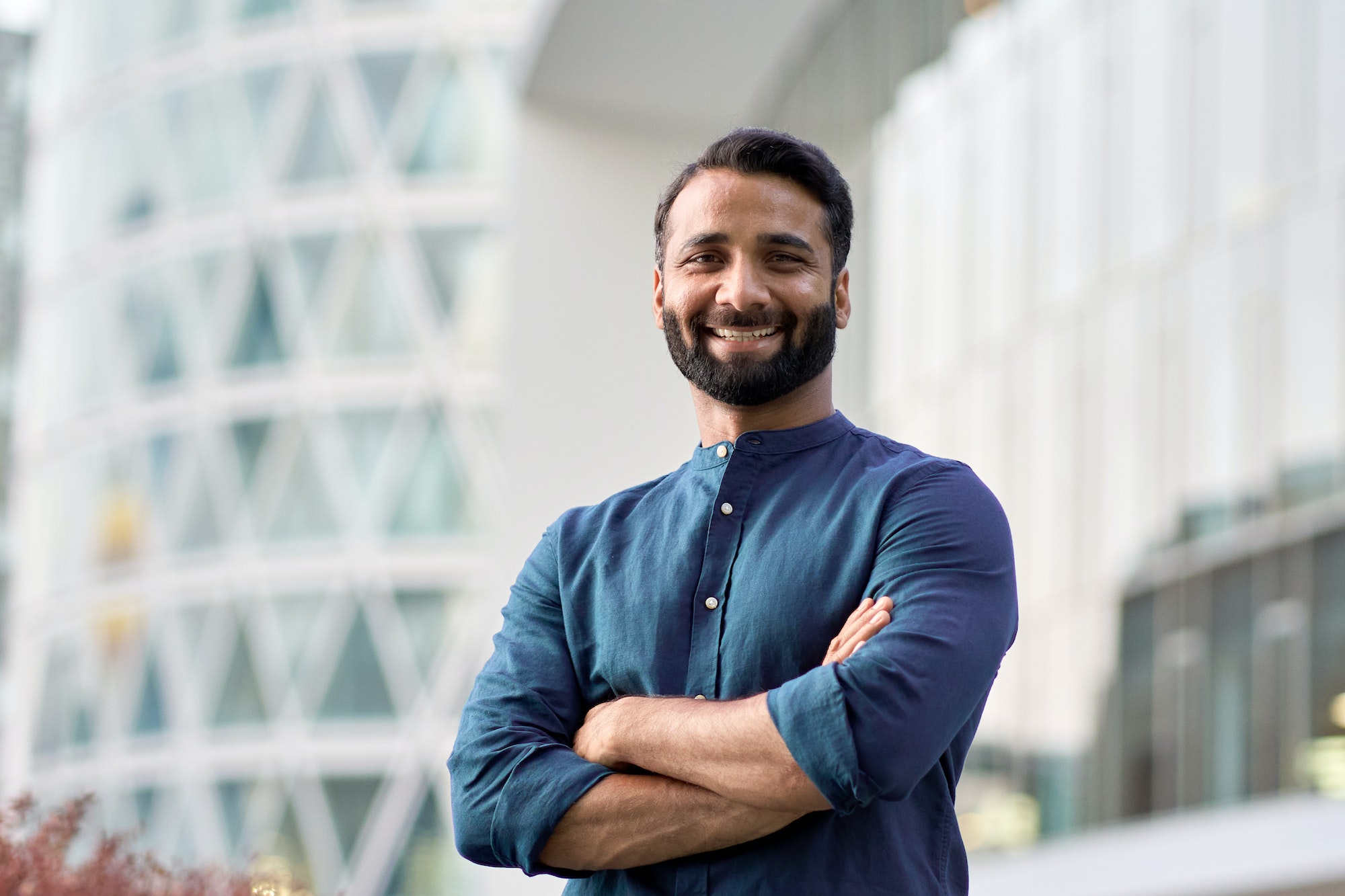 Confident happy indian business man looking at camera outdoor headshot portrait.