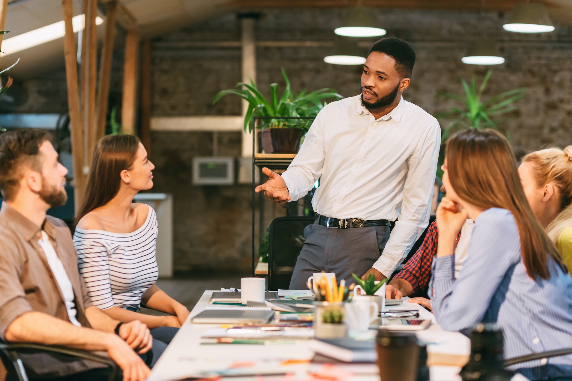 Young boss talking to employees, having board meeting